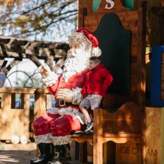 Christmas Capital of Texas kids takes picture with Santa statue
