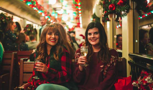 Two women with glasses of wine aboard the Grapevine Vintage Railroad's Christmas Wine Train during Christmas Capital of Texas