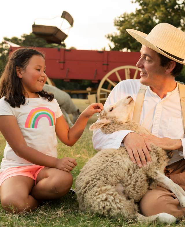 A farmhand and child with a sheep at Historic Nash Farm in Grapevine, Texas