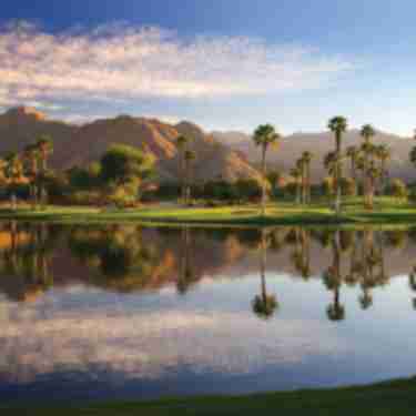 Beautiful lake at Indian Wells Golf Resort with the mountains, palm trees and green grass.