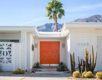 Modernism house with pretty palm tree background and orange door.