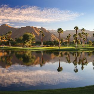 Beautiful lake at Indian Wells Golf Resort with the mountains, palm trees and green grass.