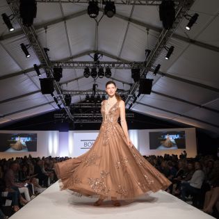 A model walks down the runway in a floor-length gown at Fashion Week El Paseo