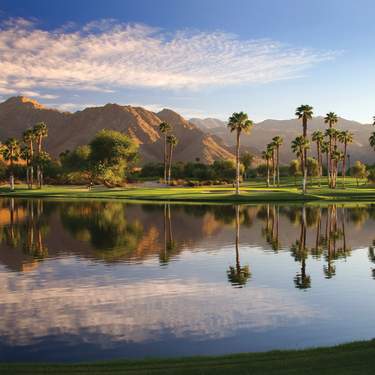 Beautiful lake at Indian Wells Golf Resort with the mountains, palm trees and green grass.