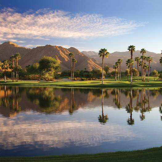Beautiful lake at Indian Wells Golf Resort with the mountains, palm trees and green grass.
