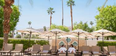 Two woman laying by the pool at Omni Rancho Mirage.