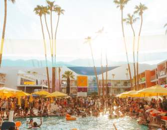 The pool area at Saguaro Hotel In Palm Springs with lots of people in and around the pool.