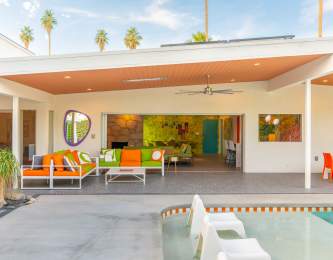 Palm Springs Vacation Rental modern patio with colorful seating, a pool, and a bright interior view featuring vibrant decor.