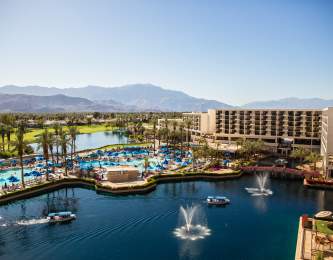 Aerial view of lake by resort and mountains in background with blue sky