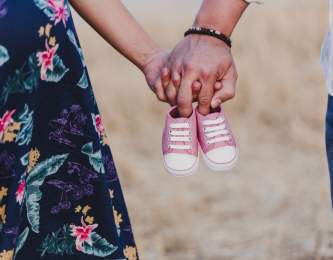 Pregnant couple holding baby shoes