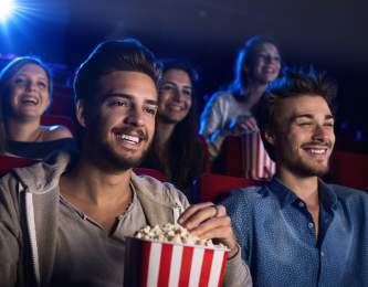 Gay men enjoying popcorn while sitting in a movie theater