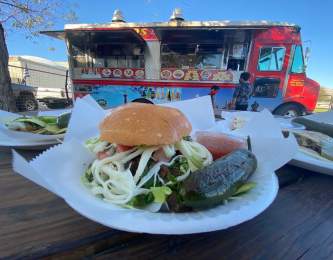 A close up of a torta. In the background a red food truck.