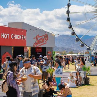 People eating with the ferris wheel in the background at the Coachella festival.