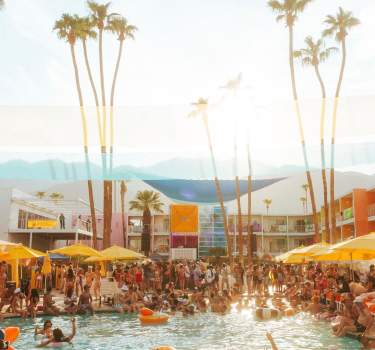 The pool area at Saguaro Hotel In Palm Springs with lots of people in and around the pool.