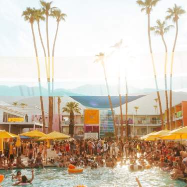 The pool area at Saguaro Hotel In Palm Springs with lots of people in and around the pool.