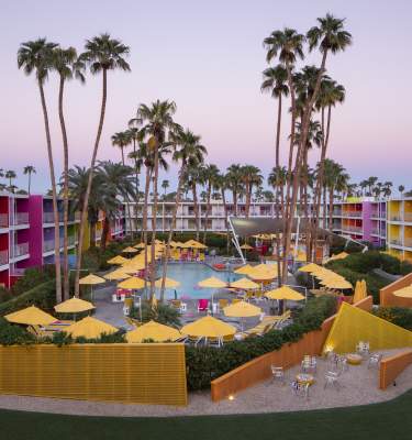 Aerial view of the pool at The Saguaro surrounded by the colorful resort buildings.