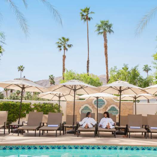 Two woman laying by the pool at Omni Rancho Mirage.