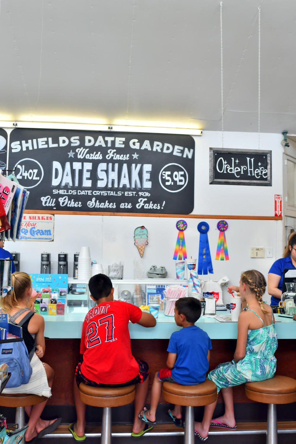 Kids sitting at a counter eating ice cream in a shop