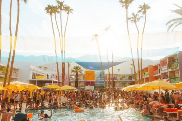 The pool area at Saguaro Hotel In Palm Springs with lots of people in and around the pool.