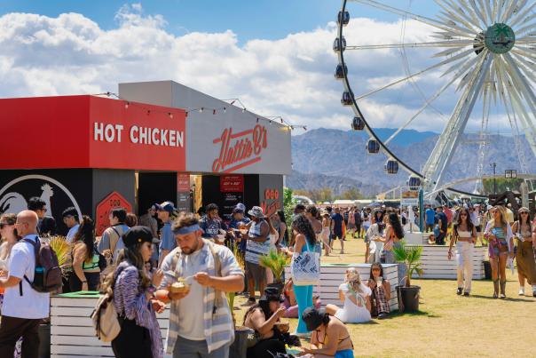 People eating with the ferris wheel in the background at the Coachella festival.