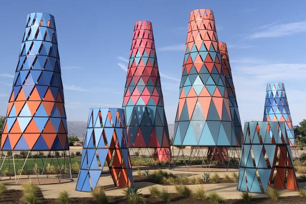 Various cone-shaped towers in shades of blue, orange, red and pink located at a park in Indio.