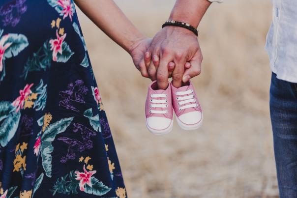 Pregnant couple holding baby shoes