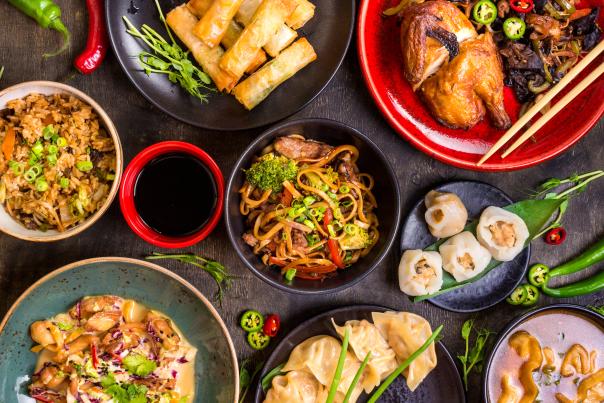 Spread of different Chinese food on black table.