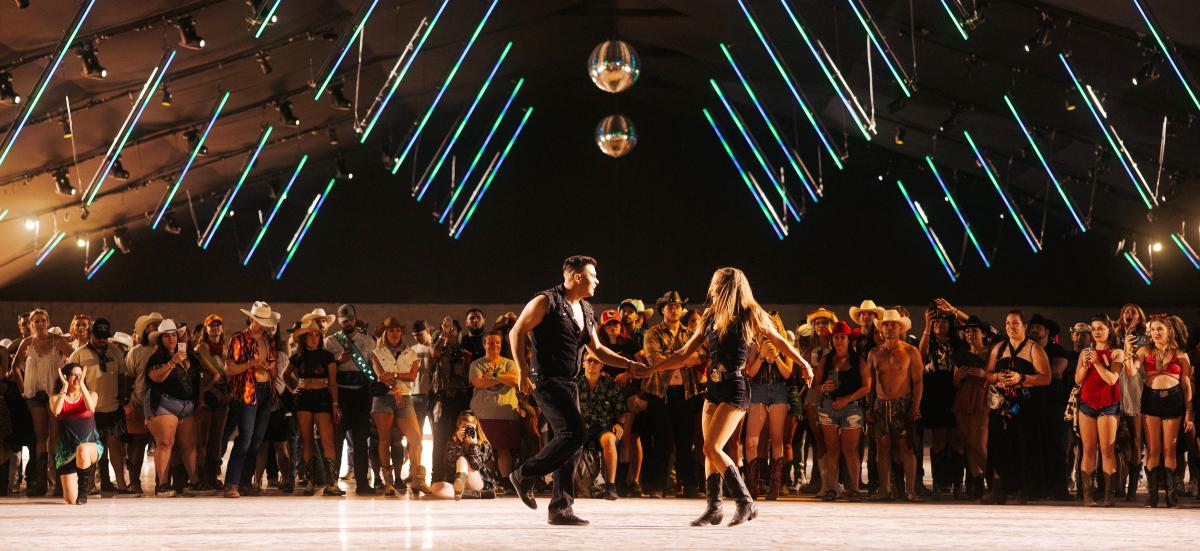 A couple dances inside a tent at Stagecoach while a crowd looks on.