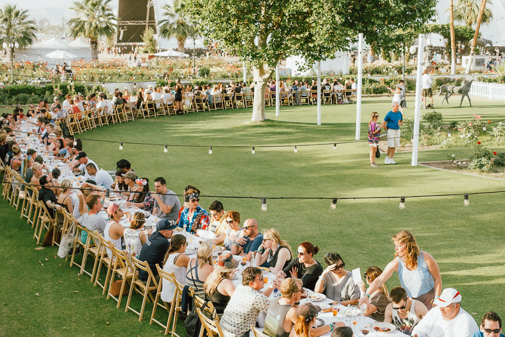 People seated at a long and winding outdoor table.