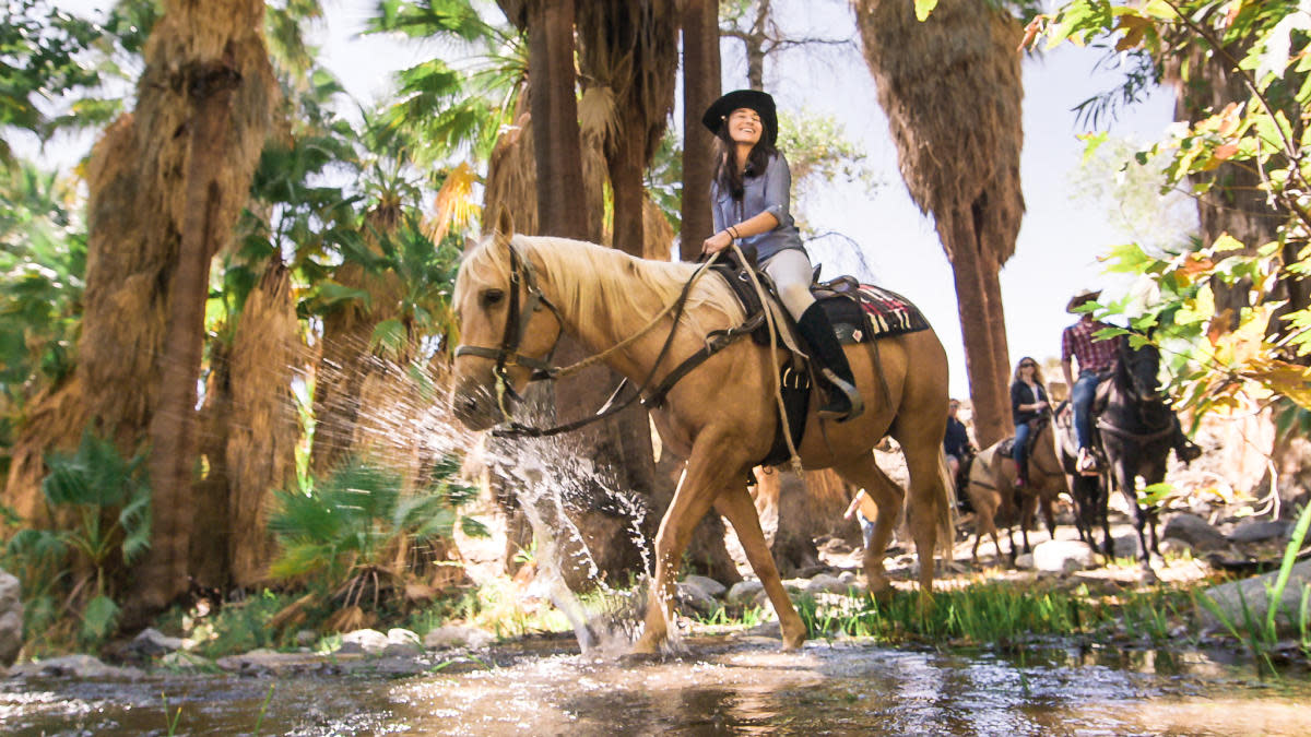 A smiling woman explores Indian Canyons on horseback with Smoke Tree Stables in Palm Springs