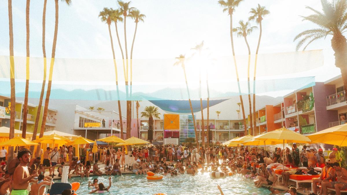The pool area at Saguaro Hotel In Palm Springs with lots of people in and around the pool.