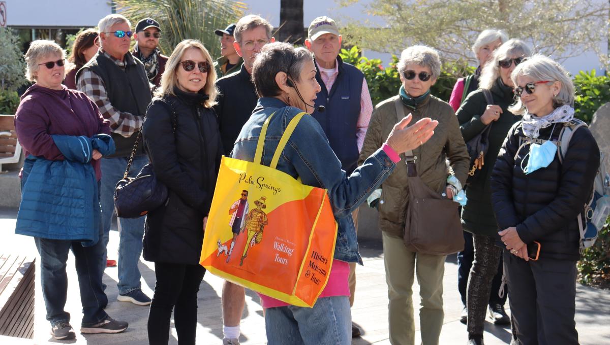 A volunteer guide leads a group of people on a walking tour.