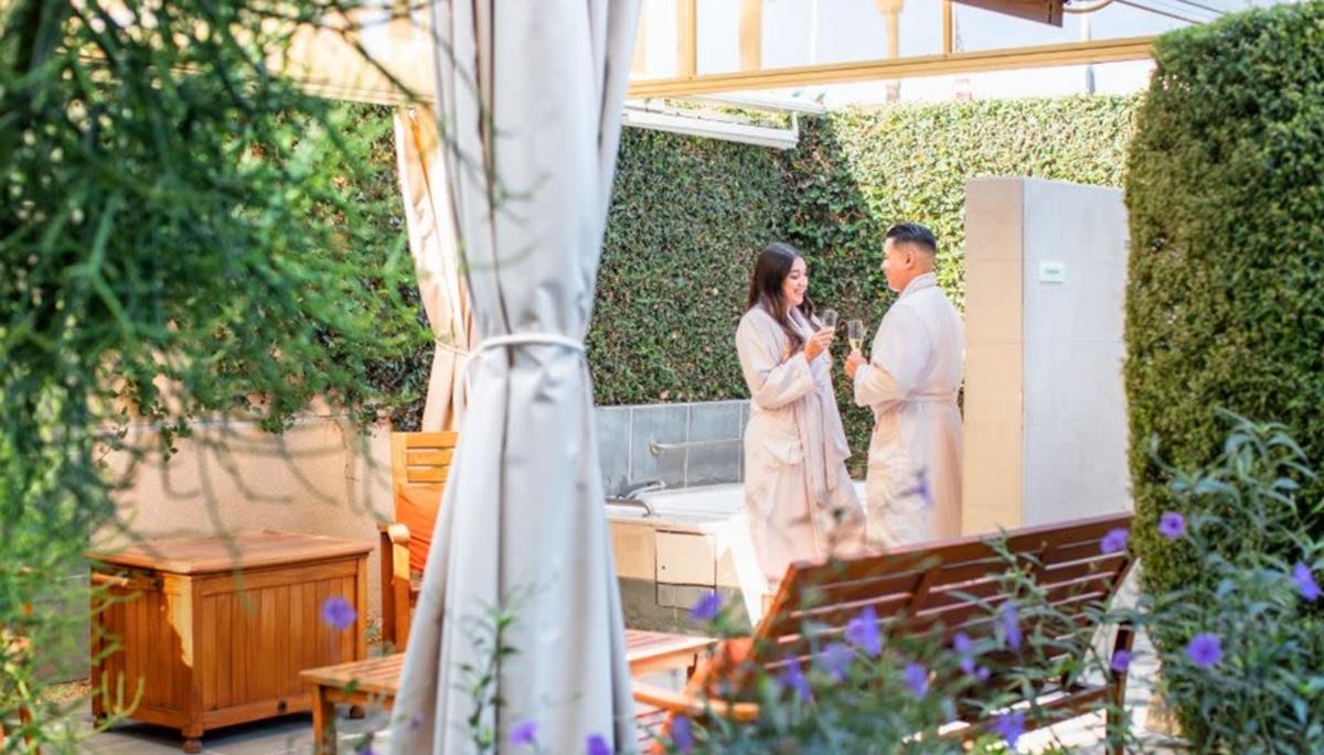 couple holding glasses of champagne in spa garden