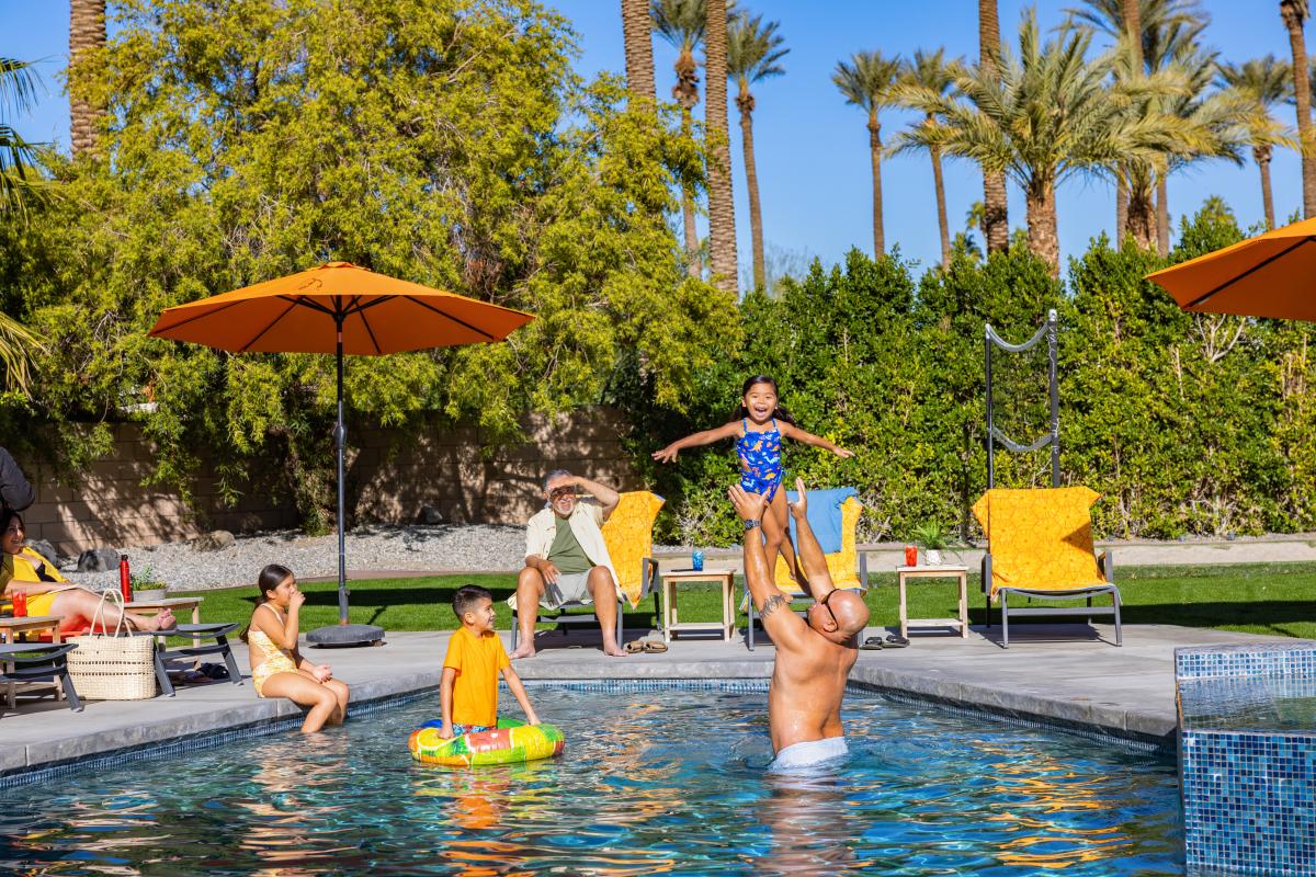 Family gathering around pool at vacation rental in Palm Springs