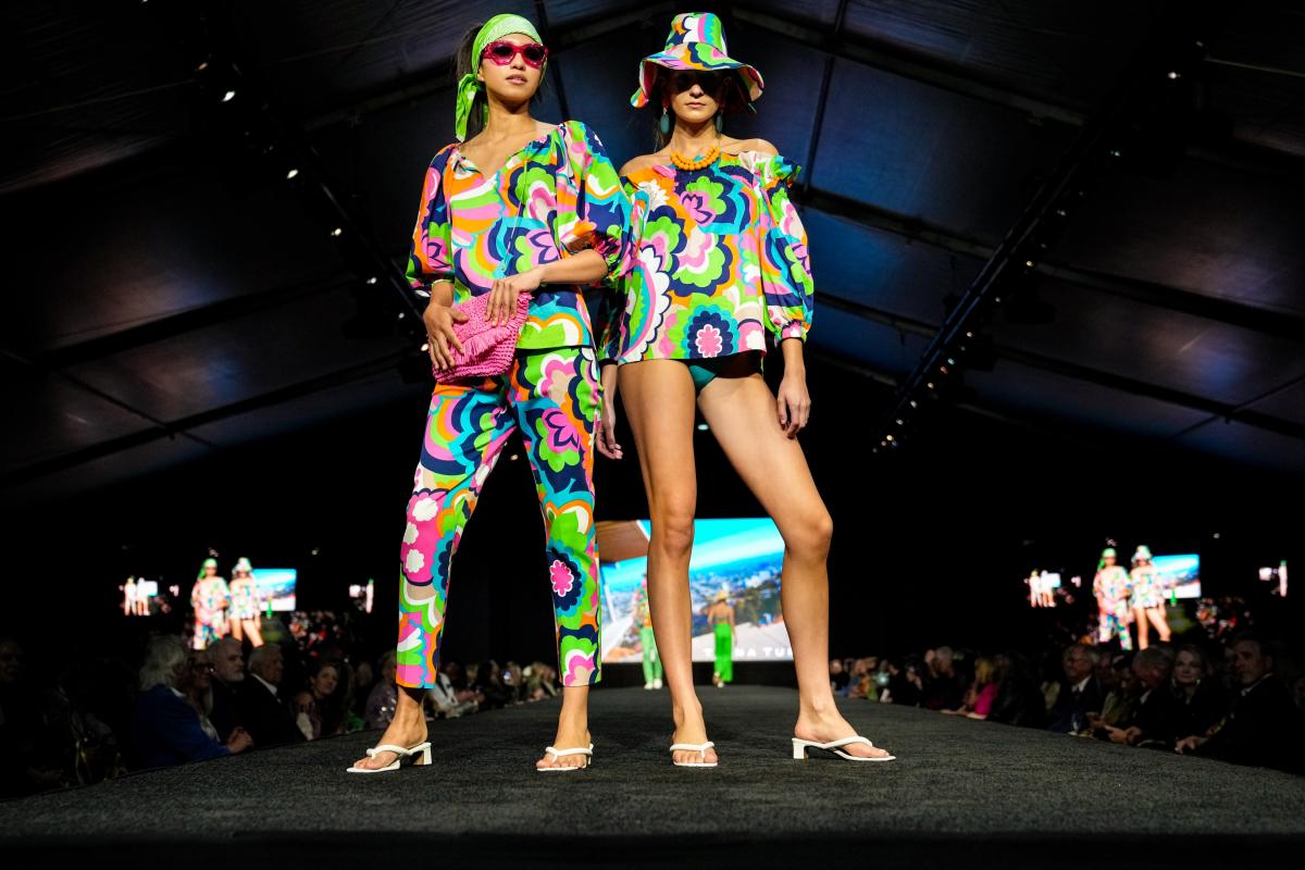 Two models wearing colorful outfits pose at the end of the runway during Fashion Week El Paseo 2023.