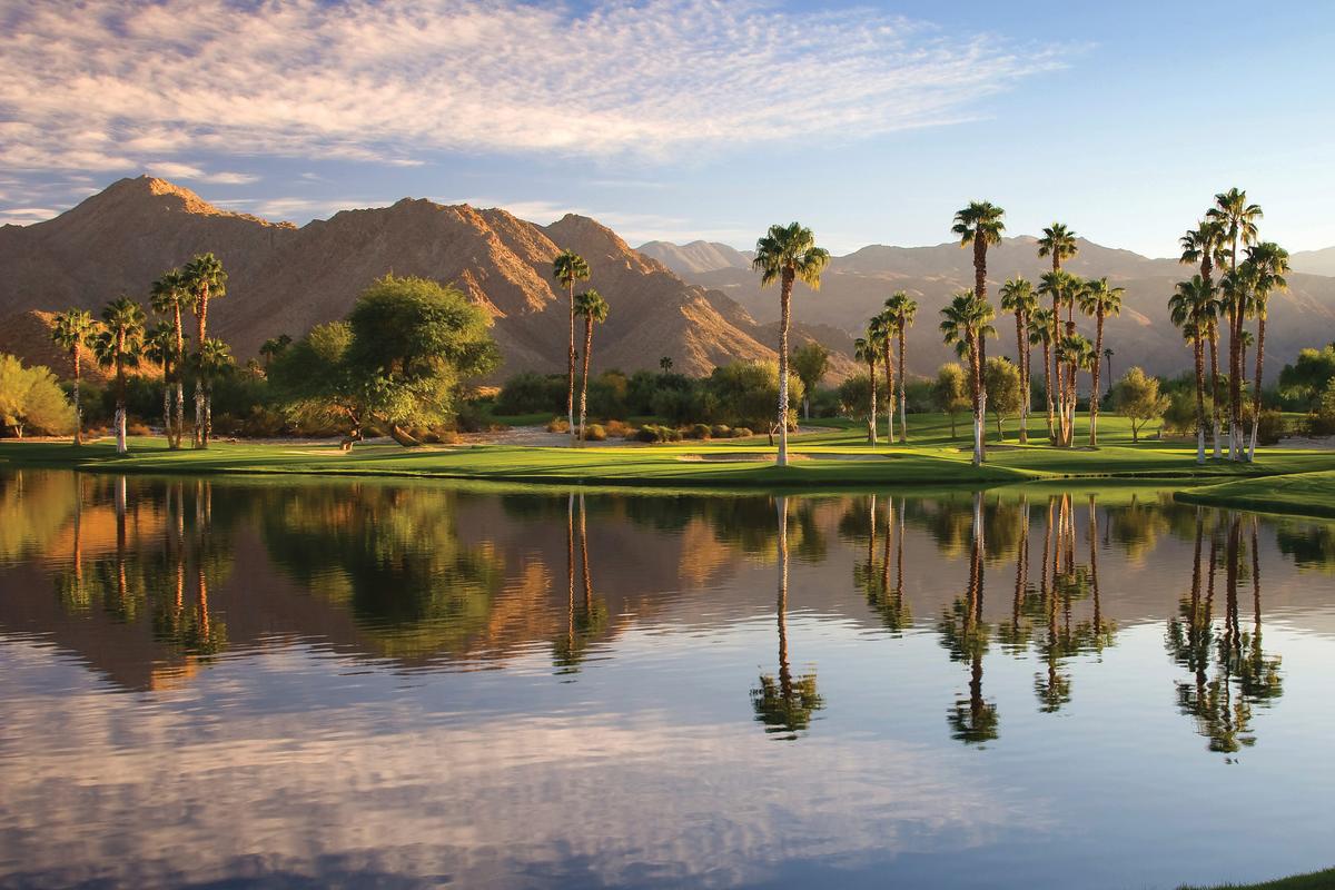 Beautiful lake at Indian Wells Golf Resort with the mountains, palm trees and green grass.