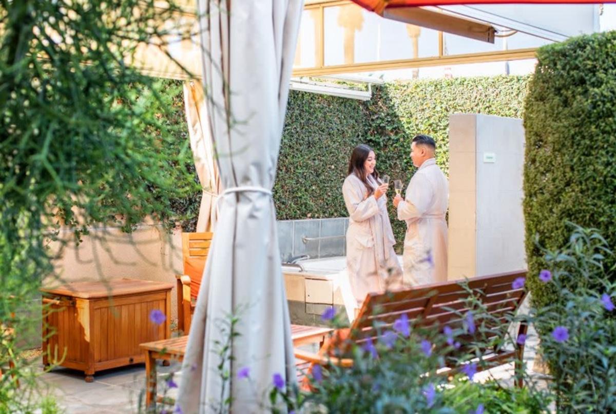 couple holding glasses of champagne in spa garden
