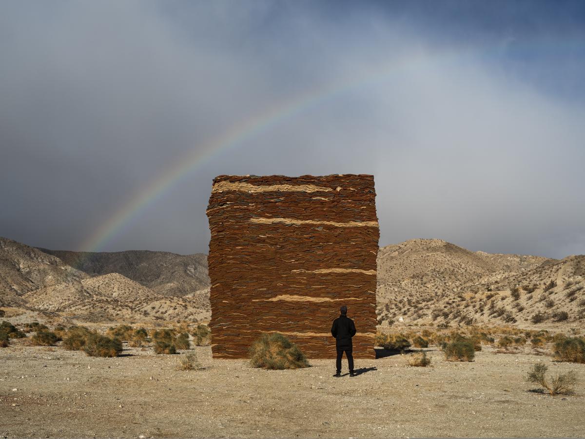 Wall of clothes art in the desert with a rainbow
