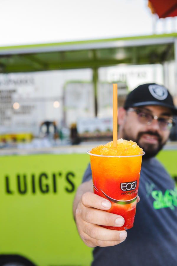 Man holding Luigi Slushi out in front of the food truck.