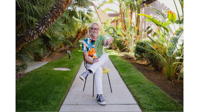 Person holding cocktail under palm trees