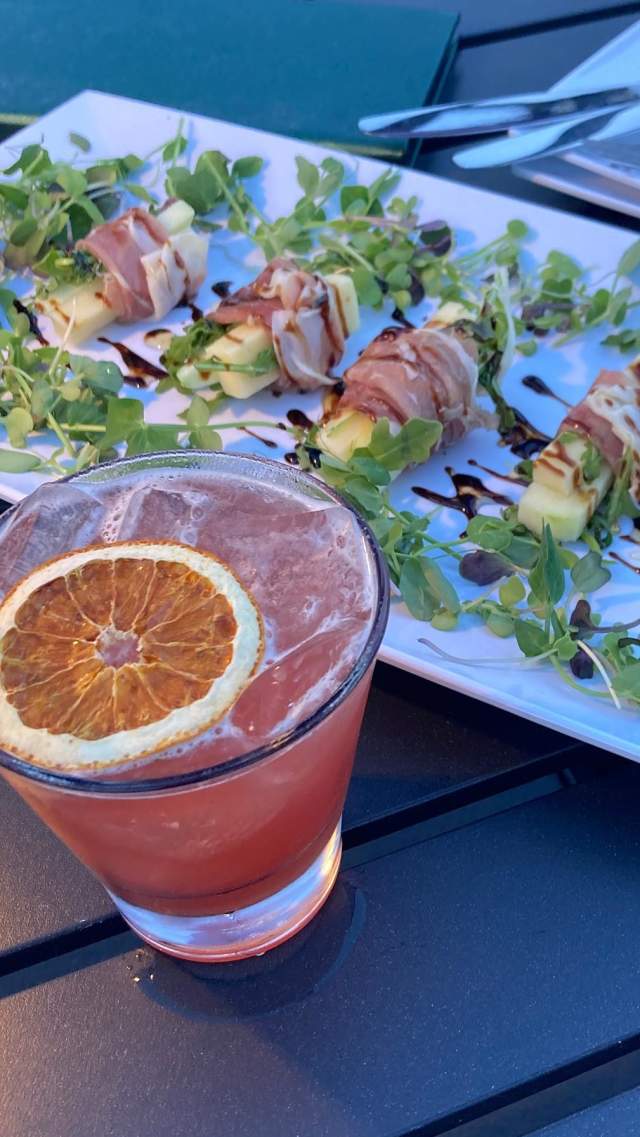 A fruity cocktail and appetizer sit on a table at Eden Rooftop Lounge in downtown Greenville, SC.