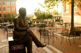A bronze statue of a Vardry McBee, framed by the golden hues of a sunrise in the background.
