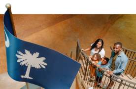 Family on stairs at the Upcountry History Museum admiring the South Carolina flag monument.