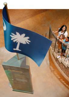Family on stairs at the Upcountry History Museum admiring the South Carolina flag monument.