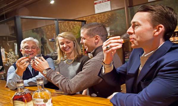Group of patrons sitting at the bar taste testing drinks at Dark Corner Distillery.