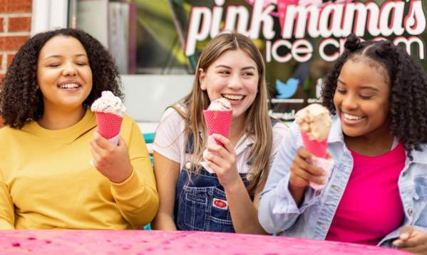 Three kids happily eat their pink ice cream cones at Pink Mama's Ice Cream in Travelers Rest, SC.