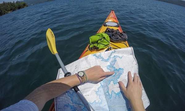 A view of a man in a kayak on a lake navigating his way to Laurel Creek Falls with a map