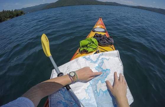 A view of a man in a kayak on a lake navigating his way to Laurel Creek Falls with a map