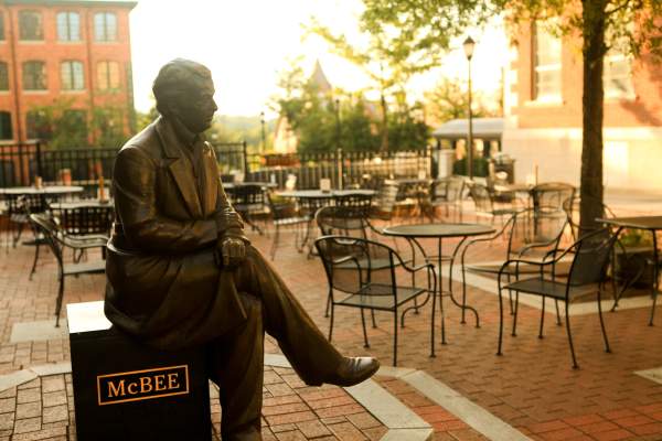 A bronze statue of a Vardry McBee, framed by the golden hues of a sunrise in the background.