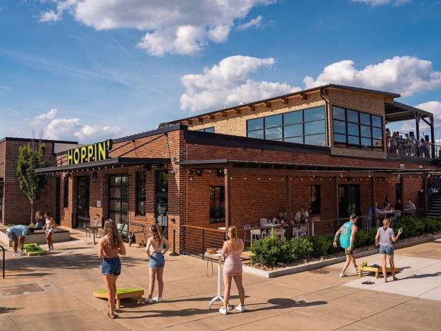 People playing cornhole outside of Hoppin' GVL, a taproom in downtown Greenville, SC.